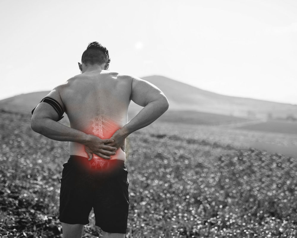 Rearview shot of a young man exercising with an injury highlighted by cgi